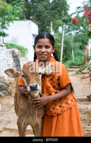 Giovani villaggio indiano ragazza abbracciando un vitello in un territorio rurale villaggio indiano. Andhra Pradesh, India Foto Stock