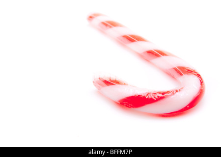 Chiave di alta immagine di un candy cane con messa a fuoco poco profonde e copyspace contro uno sfondo bianco. Foto Stock