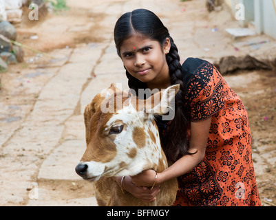 Giovani villaggio indiano ragazza abbracciando un vitello in un territorio rurale villaggio indiano. Andhra Pradesh, India Foto Stock