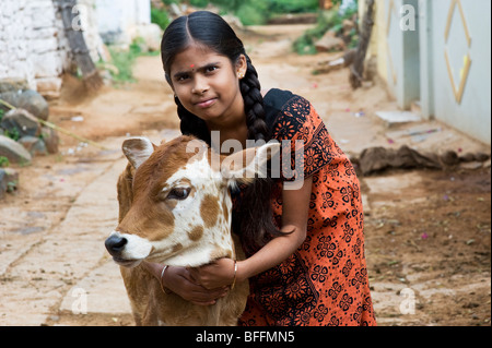 Giovani villaggio indiano ragazza abbracciando un vitello in un territorio rurale villaggio indiano. Andhra Pradesh, India Foto Stock