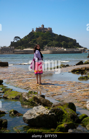 Ritratto di una femmina cinese turista che attraversa il Selciato del maremoto a St Michaels Mount, Marazion, vicino Penzance in Cornovaglia, Regno Unito Foto Stock