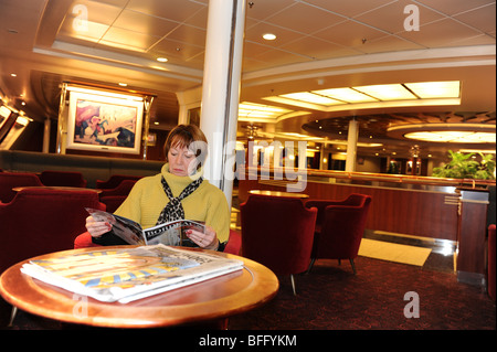 Passeggero femmina leggendo una rivista su una croce di Seafrance traghetto di canale Foto Stock