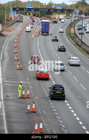 Autostrade lavoratore mettendo i coni di traffico su autostrada M6 incrocio con la M54 Foto Stock