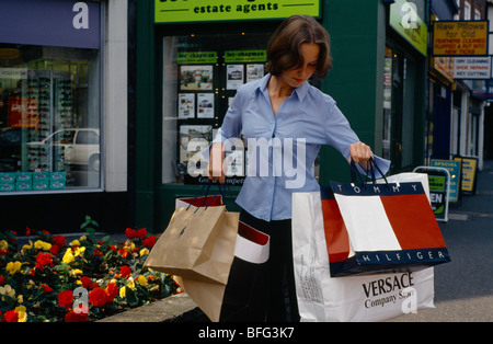 Giovane donna che trasportano designer borse in strada Foto Stock