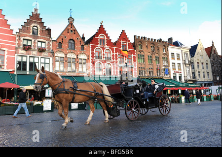 I turisti in giro per la città da cavallo e carrozza nel Markt a Bruges in Belgio in Europa Foto Stock