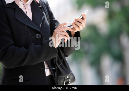 Imprenditrice tramite telefono cellulare, metà sezione Foto Stock