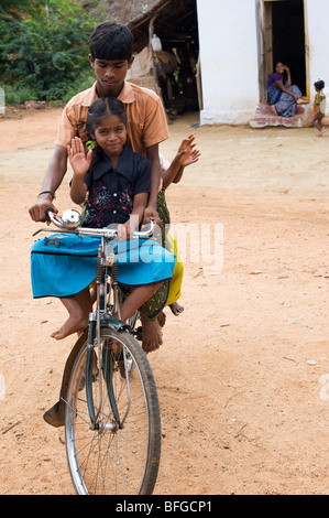 Adolescente indiano e i bambini in sella ad una bicicletta in una zona rurale villaggio indiano. Andhra Pradesh, India Foto Stock