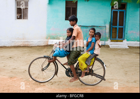 Adolescente indiano e i bambini in sella ad una bicicletta in una zona rurale villaggio indiano. Andhra Pradesh, India Foto Stock