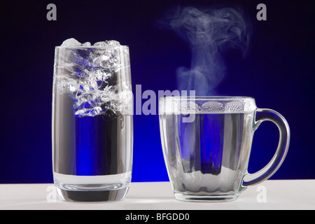 Ghiaccio acqua vapore. Un bicchiere di acqua e ghiaccio e una tazza di tè di calda acqua di cottura a vapore. Foto Stock