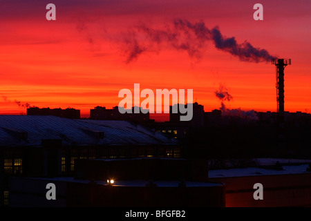 Rosso tramonto sulla città industriale skyline con fumatori Camino. Foto Stock