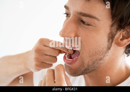 Metà di uomo adulto il filo interdentale i denti in bagno, close up Foto Stock