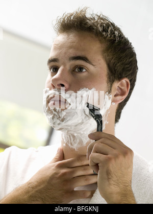 Giovane uomo rasatura con una lama di rasoio Foto Stock