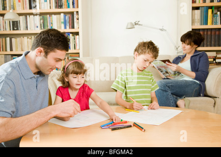 Padre a giocare con i bambini e la madre rilassante Foto Stock