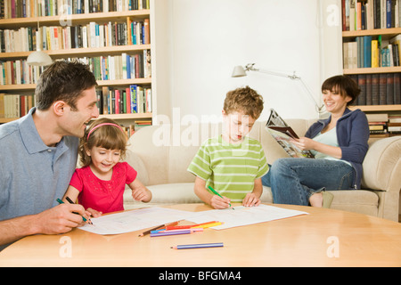 Padre a giocare con i bambini e la madre rilassante Foto Stock