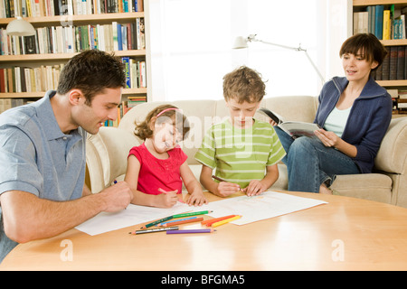 Padre a giocare con i bambini e la madre rilassante Foto Stock