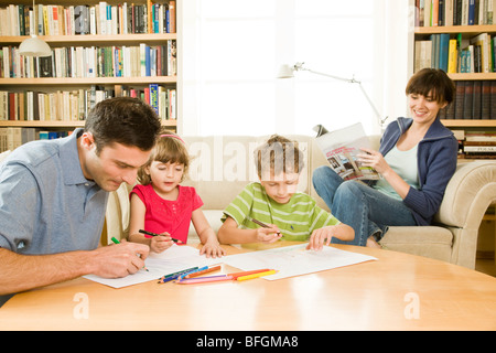 Padre a giocare con i bambini e la madre rilassante Foto Stock