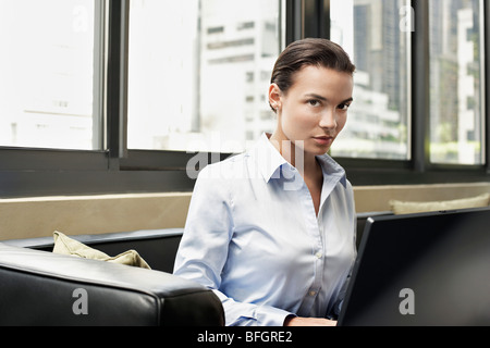 Business donna seduta su un divano con lap top Foto Stock