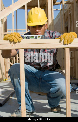 Operaio edile utilizzando la livella sulla costruzione Foto Stock