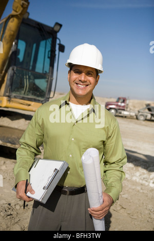 Geometra azienda blueprint sul sito in costruzione, ritratto Foto Stock