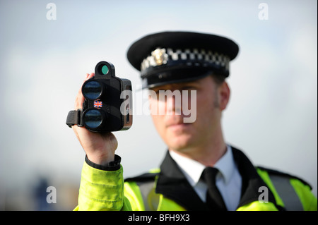 Un poliziotto dalla Polizia del Sussex utilizza una mano fotocamera velocità sul lato di una strada trafficata Foto Stock