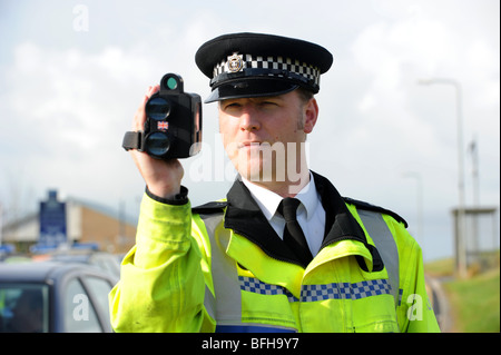 Un poliziotto dalla Polizia del Sussex utilizza una mano fotocamera velocità sul lato di una strada trafficata Foto Stock