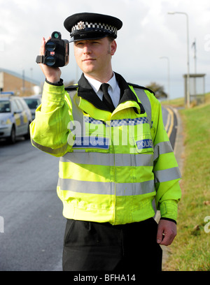 Un poliziotto dalla Polizia del Sussex utilizza una mano fotocamera velocità sul lato di una strada trafficata Foto Stock