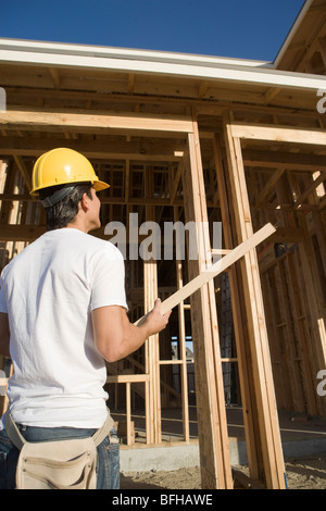 Operaio edile portante trave in legno Foto Stock