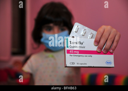 Una bambina indossa un medico di maschera facciale e detiene un pacco di Tamiflu compresse contro l'influenza suina, 30 ottobre 2009. Foto Stock