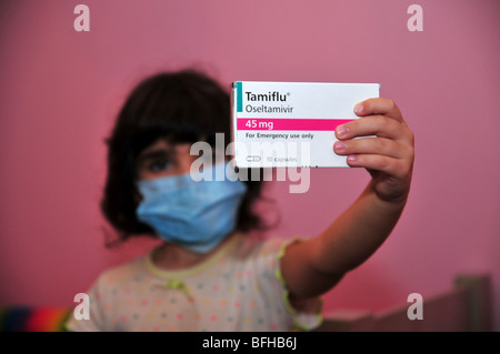 Una bambina indossa un medico di maschera facciale e detiene un pacco di Tamiflu compresse contro l'influenza suina, 30 ottobre 2009. Foto Stock