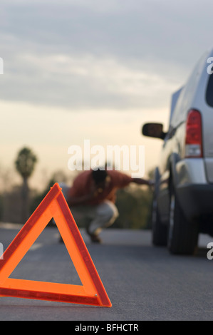 Il triangolo di avvertenza di fronte ripartiti in auto, l'uomo in background Foto Stock