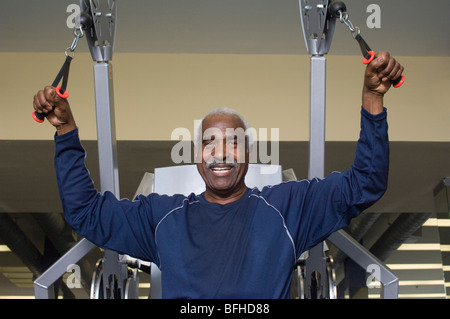 Senior Uomo al lavoro sulla macchina di sollevamento pesi Foto Stock