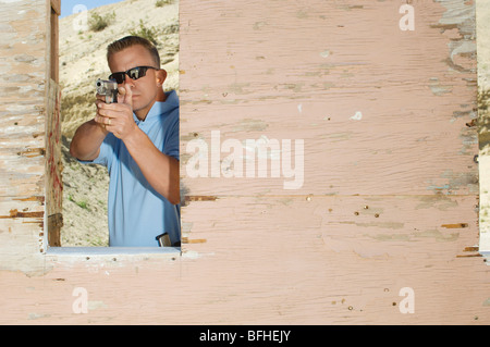 Man mano di puntamento pistola a poligono di tiro Foto Stock