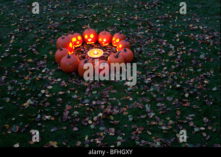 Le zucche scolpite in un cerchio al crepuscolo attorno ad una torta di zucca di Halloween notte Foto Stock