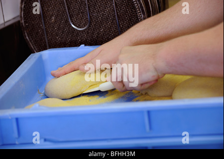 Impasto per pizza che viene rimosso da un vassoio pronto per la laminazione ad un take away pizzeria. Foto Stock