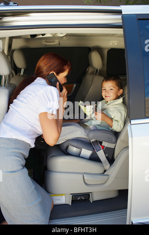Business donna utilizzando il telefono cellulare con il figlio in auto Foto Stock