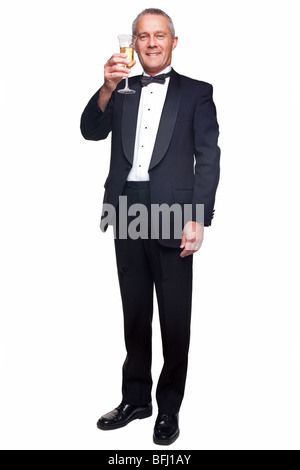 Un maschio maturo indossando un nero Tuxedo e bow tie sollevando un bicchiere di champagne, isolata su uno sfondo bianco. Foto Stock