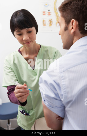 Medico iniettando il paziente di sesso maschile in ospedale Foto Stock