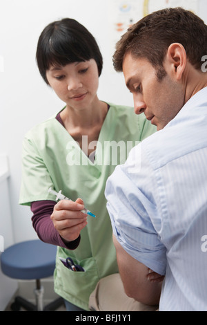 Medico iniettando il paziente di sesso maschile in ospedale Foto Stock