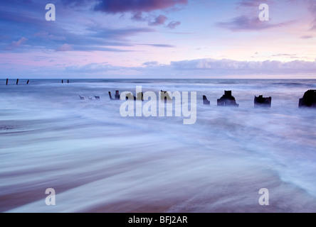 Abbandonate le difese del mare alla prima luce a Happisburgh sulla costa di Norfolk Foto Stock