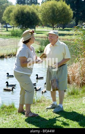 Coppia senior in piedi nella parte anteriore del flusso, parlando Foto Stock