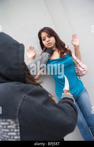 Donna con cappuccio rubando la giovane donna con il coltello Foto Stock