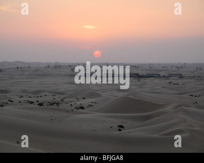 Sun impostazione oltre le dune di sabbia del deserto al di fuori citta' di Abu Dhabi nel mese di novembre, EMIRATI ARABI UNITI Foto Stock