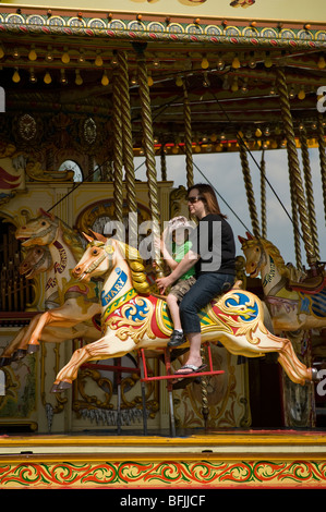 La madre e il giovane ragazzo in sella insieme su steam galloper fiera rotonda Foto Stock