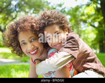 Madre dando figlio piggy back ride Foto Stock