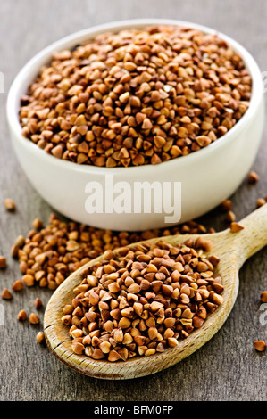 Semi di grano saraceno sul cucchiaio di legno e nel recipiente Foto Stock