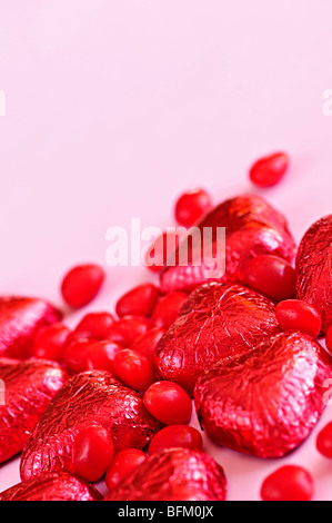 Rosso di San Valentino di caramelle e la lamina di cioccolatini incartati su sfondo rosa Foto Stock