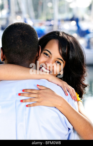 Ritratto di giovane e bella donna che abbraccia il ragazzo in piedi al porto Foto Stock