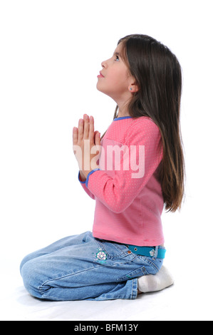 Bambina a pregare con le mani insieme su uno sfondo bianco Foto Stock