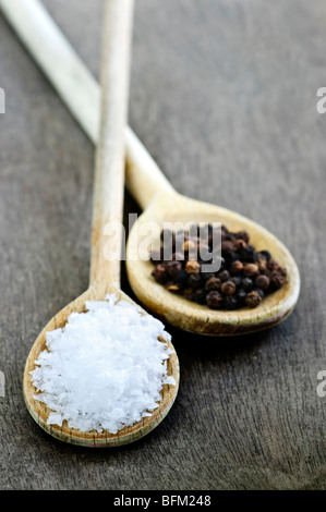 Sale marino e pepe intero su cucchiai di legno Foto Stock