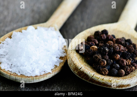 Sale marino e pepe intero su cucchiai di legno Foto Stock